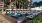 a pool with lounge chairs and umbrellas by a building